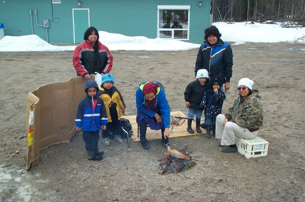 Children watch as Delia prepares duck over open flame.