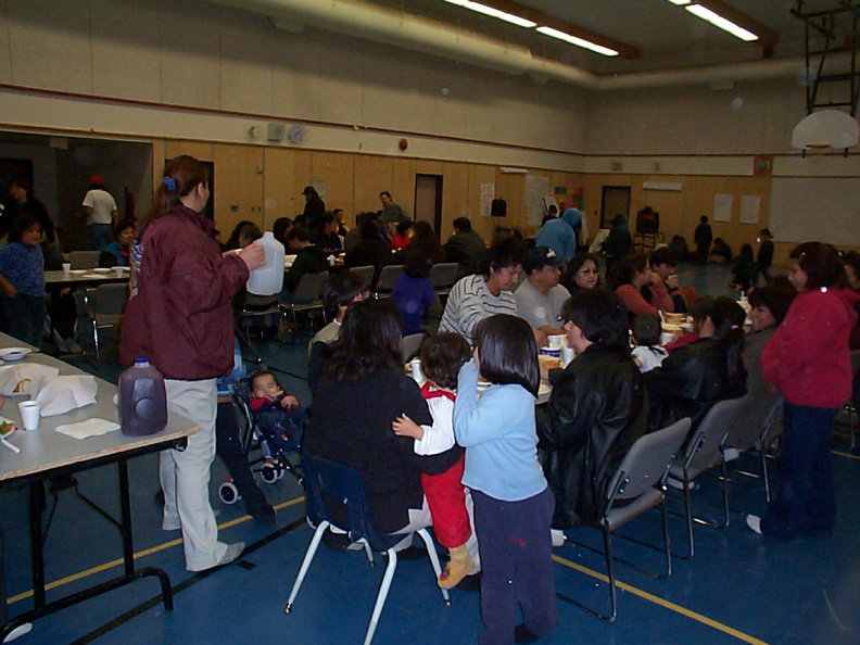 People are eating and volunteers serving food to community members.
