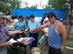 David Neegan working over a hot frying pan to give Jerry Pokrupa a bannock dog.