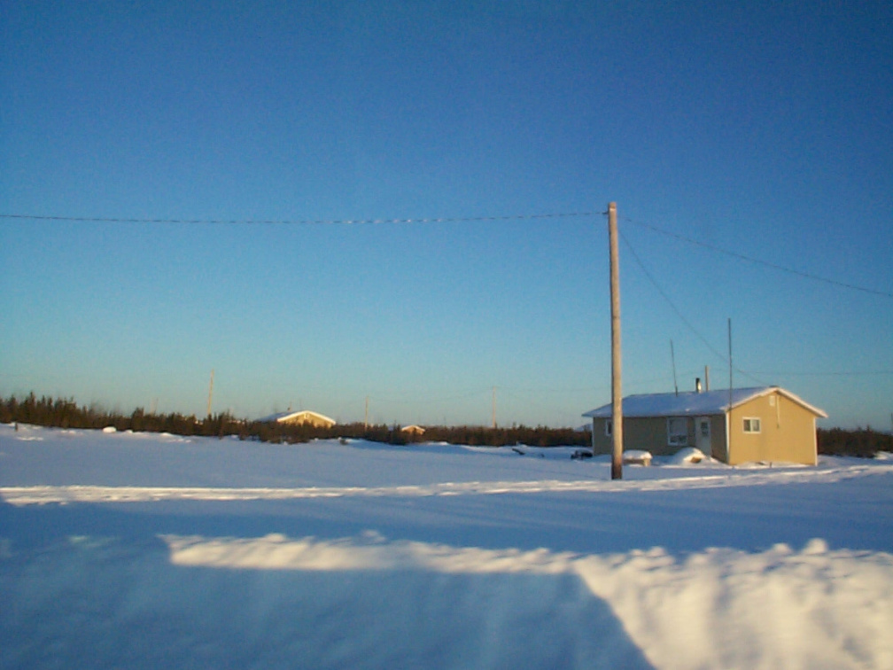 A veiw of the house with hydro poles. They used to have a community generator but that broke down and now depend on their own ge