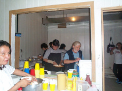 In this photo we can see the kitchen people making plates for the youth to eat first.